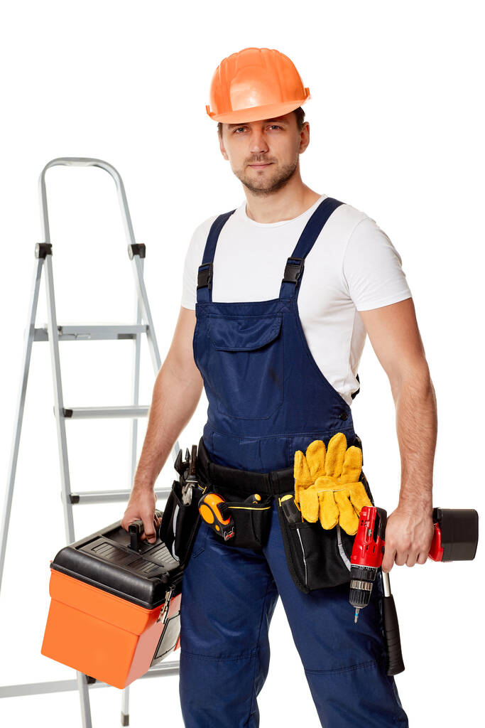 reparador caucasiano trabalhador em uniforme e capacete segurando chave de fenda sem fio
. - Foto, Imagem