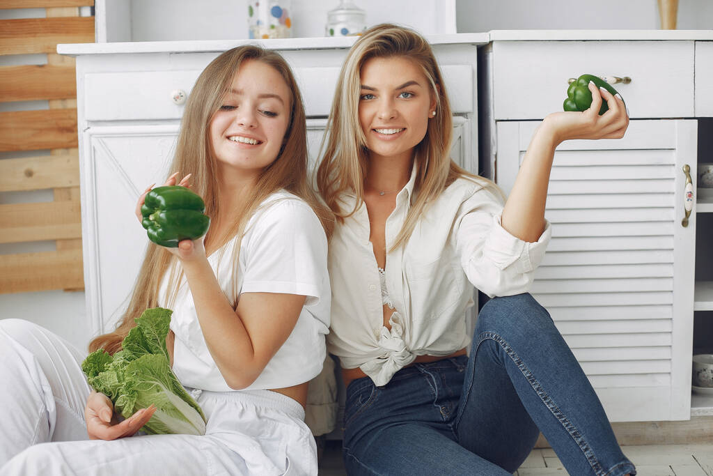 Όμορφα και σπορ κορίτσια σε μια κουζίνα με λαχανικά - Φωτογραφία, εικόνα
