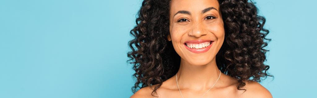 cosecha horizontal de feliz afroamericano chica sonriendo aislado en azul
 - Foto, imagen