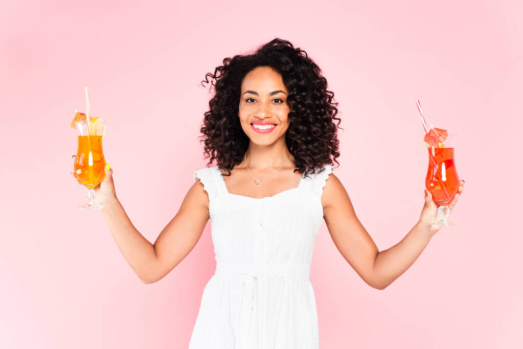 felice ragazza afro-americana che tiene cocktail sul rosa  - Foto, immagini