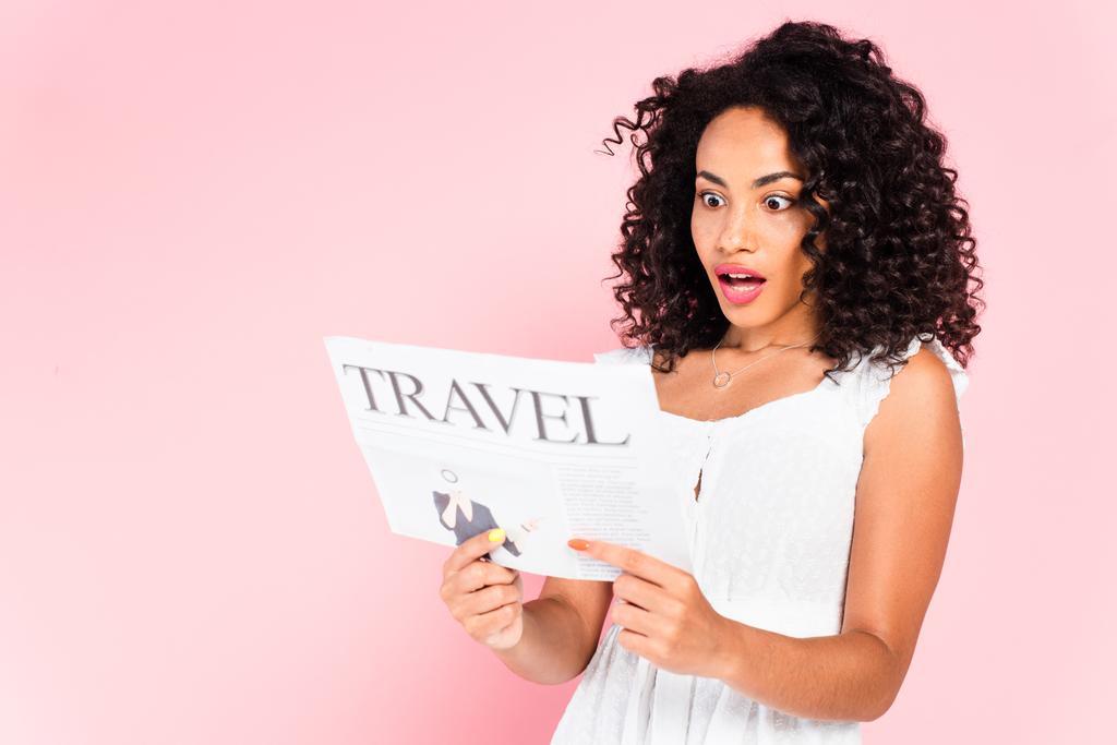 überrascht afrikanisch-amerikanische Mädchen liest Reisezeitung isoliert auf rosa  - Foto, Bild