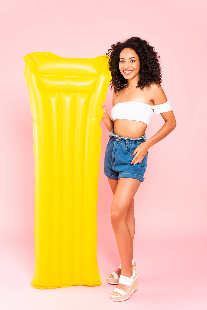 happy african american girl standing near inflatable mattress on pink  - Photo, Image