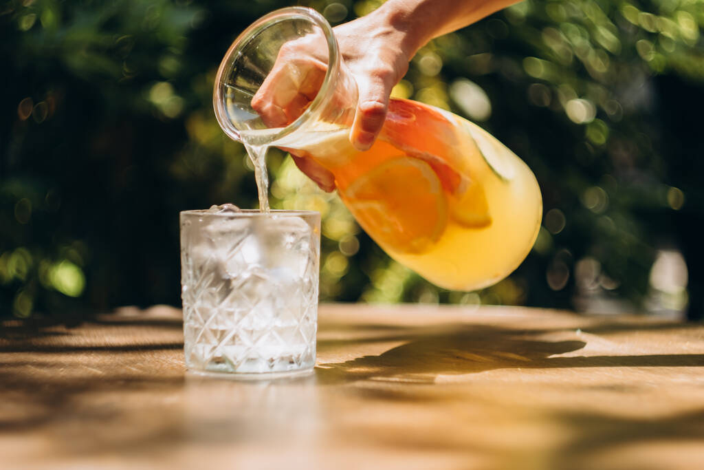 Стакан лимонада со льдом на столике в летнем дворе - Фото, изображение