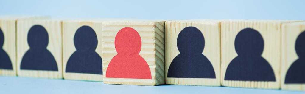 linha de blocos de madeira com ícones humanos preto e vermelho no fundo azul, conceito de liderança, tiro panorâmico
 - Foto, Imagem