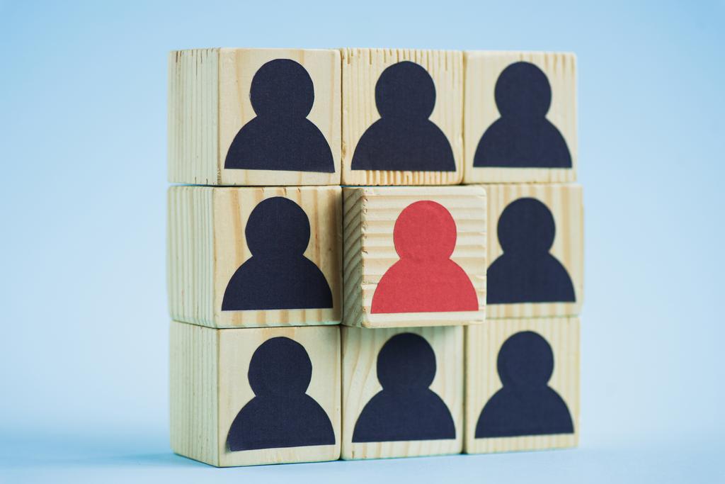 carré de blocs de bois avec des icônes humaines noires et rouges sur fond bleu, concept de leadership - Photo, image