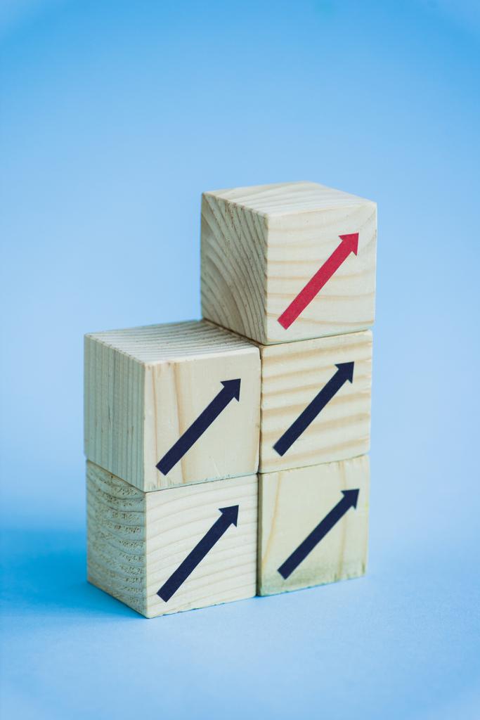 houten blokken met zwarte en rode pijlen op blauwe achtergrond, leiderschapsconcept  - Foto, afbeelding