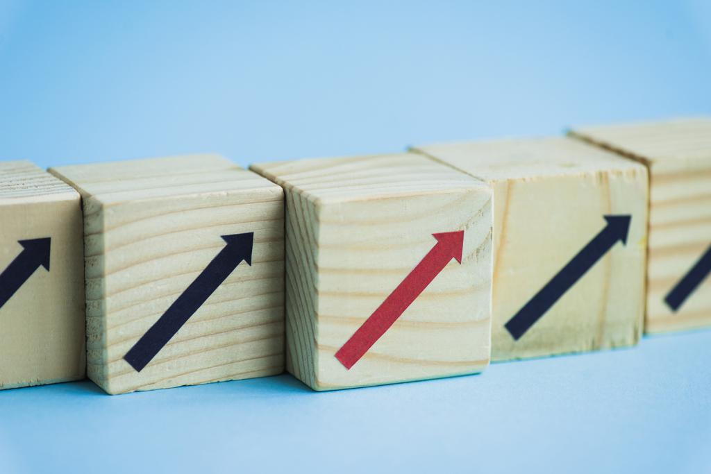 vue rapprochée des blocs de bois avec des flèches noires et rouges sur fond bleu, concept de leadership  - Photo, image