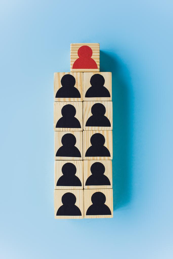 верхний вид деревянных блоков с черными и красными человеческими иконами на синем фоне, концепция лидерства - Фото, изображение