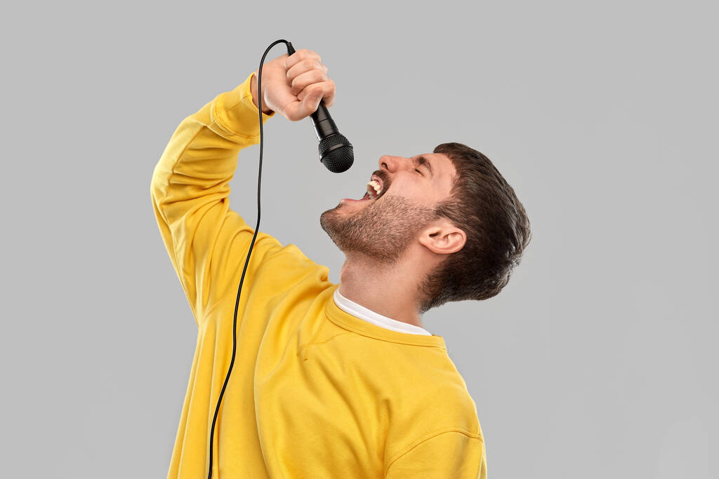 homem de camisola amarela com microfone cantando
 - Foto, Imagem