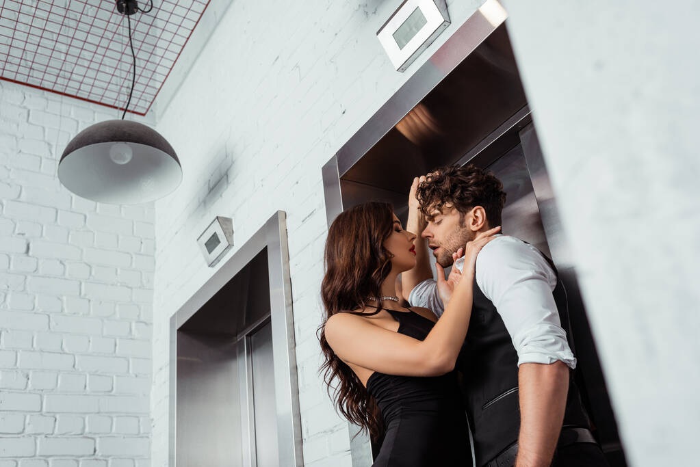 Foco seletivo de mulher abraçando homem bonito em camisa e colete perto do elevador
  - Foto, Imagem
