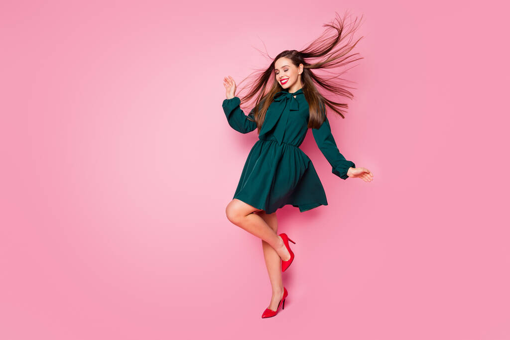 Teljes hosszúságú fotó bájos elegáns hölgy vidám hangulatú táncos diákok esemény élvezni hosszú haj repülés viselni rövid zöld ruha piros magassarkú elszigetelt pasztell rózsaszín háttér - Fotó, kép