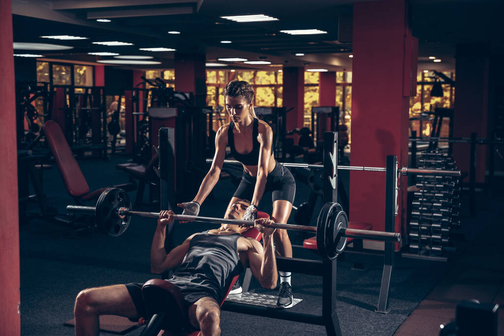 Beautiful young sporty couple training, workout in gym together - Photo, Image