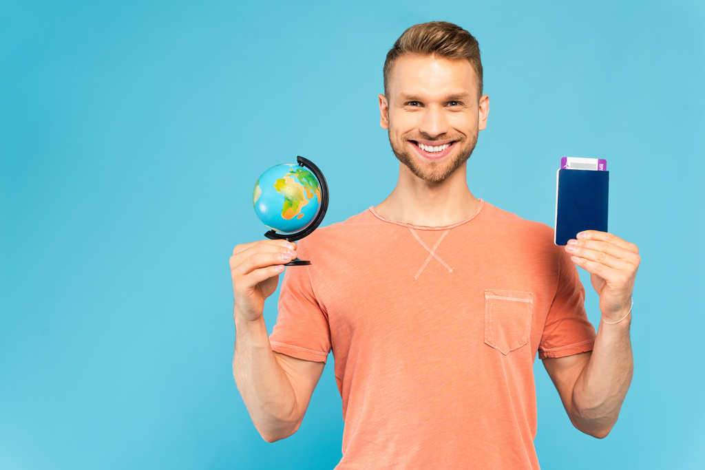 glücklicher Mann mit Pass und Globus auf blauem Grund - Foto, Bild
