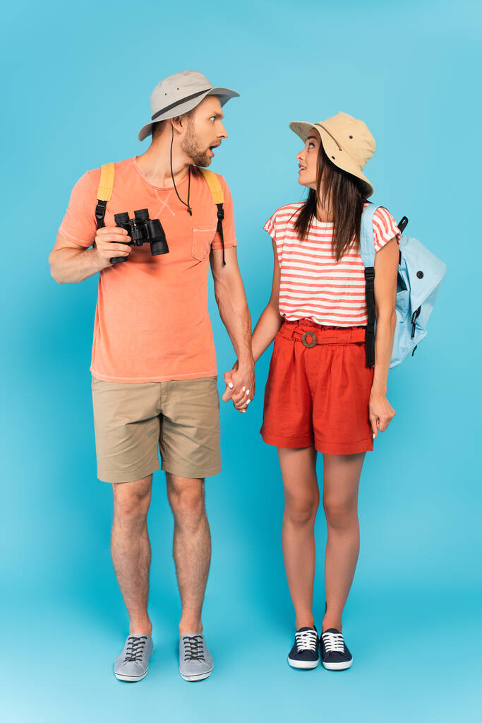 帽子をかぶったカップルが手を取り合って青い服を着て - 写真・画像