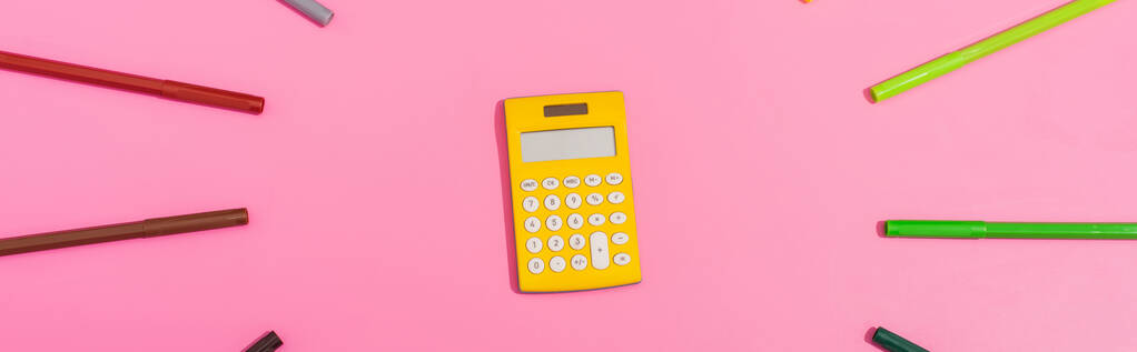 top view of calculator in frame of color felt-tip pens on pink, horizontal image - Photo, Image