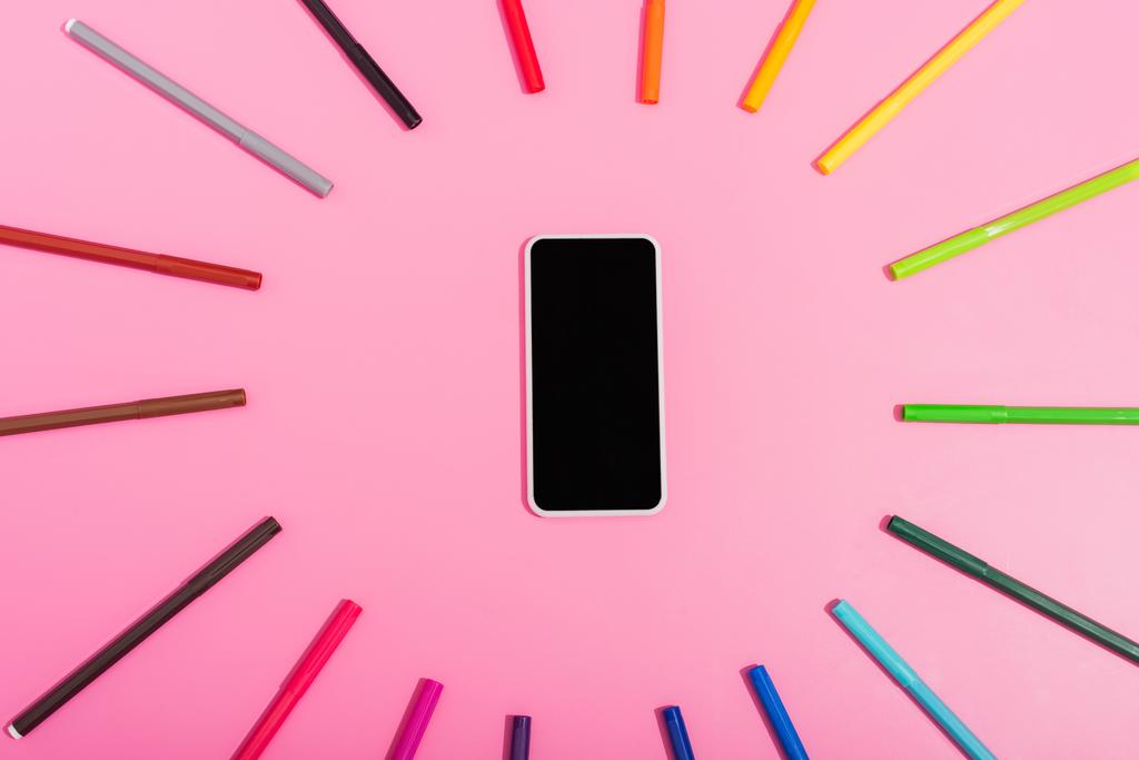 bovenaanzicht van smartphone met blanco scherm omlijst door kleur vilt tip pennen op roze - Foto, afbeelding