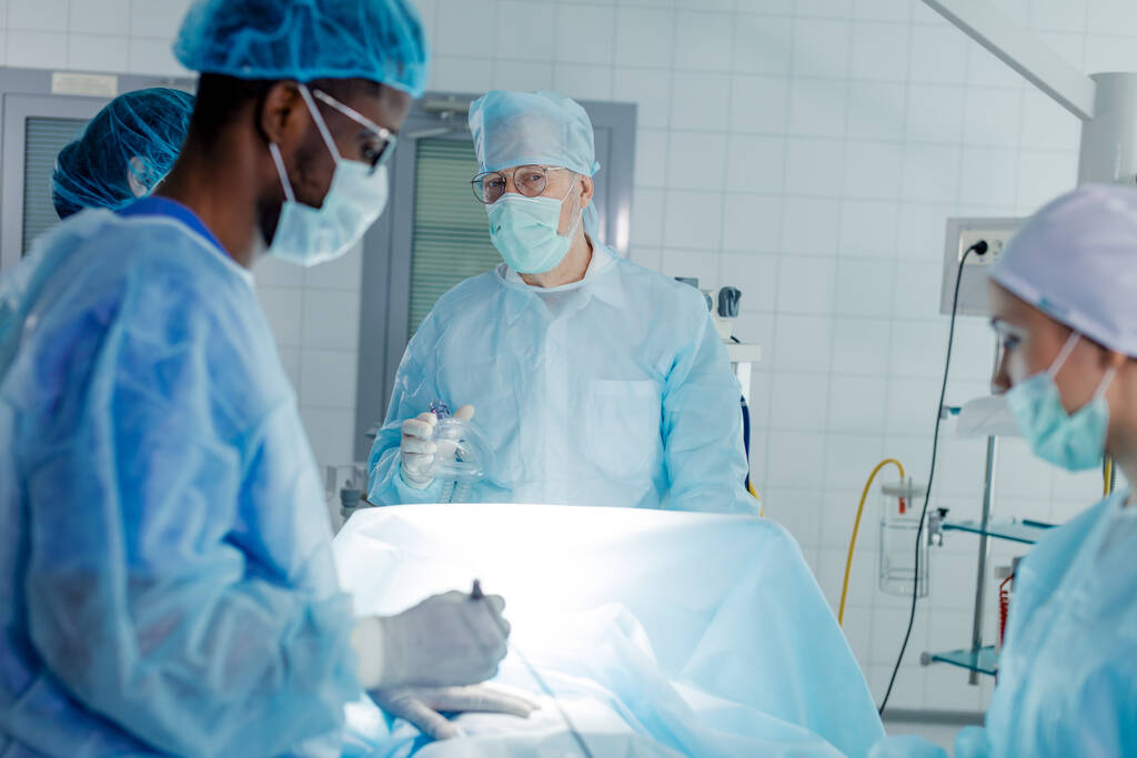 профессиональный талантливый хирург, стоящий за кроватью - Фото, изображение