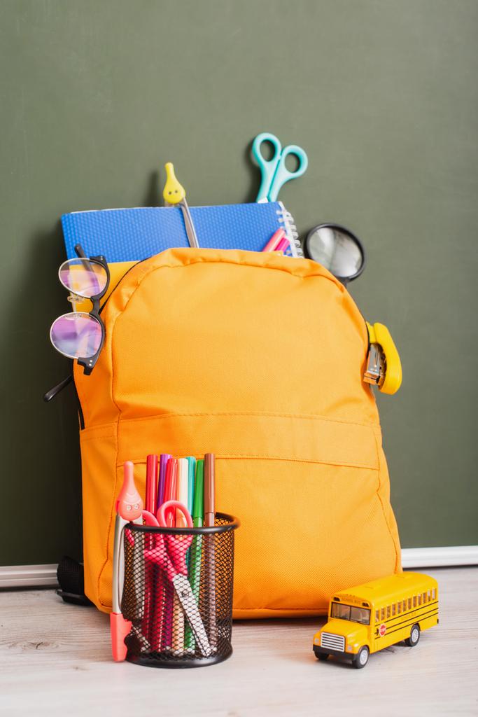 mochila escolar cheia de artigos de papelaria perto de porta-caneta e modelo de ônibus escolar
 - Foto, Imagem