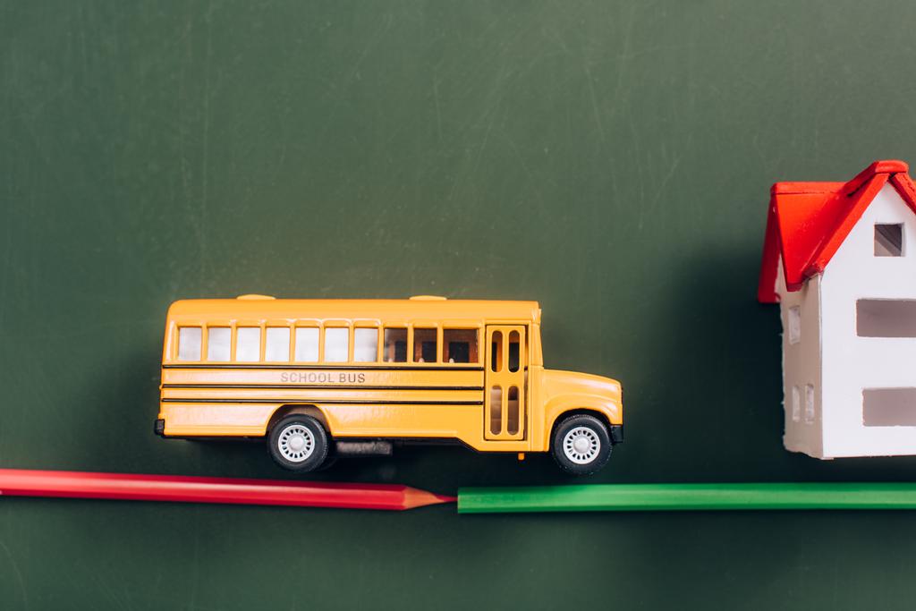widok z góry autobusu szkolnego i modeli domów na drodze wykonane z ołówków na zielonej tablicy - Zdjęcie, obraz
