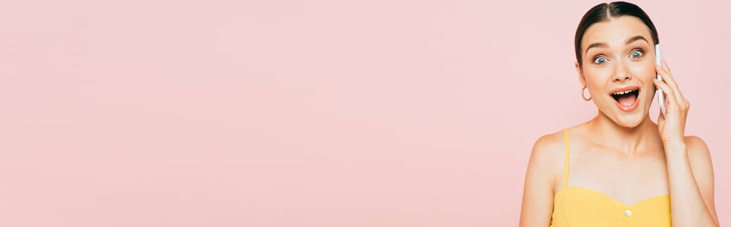 podekscytowana brunetka młoda kobieta mówi na smartfonie odizolowany na różowy, panoramiczne ujęcie - Zdjęcie, obraz
