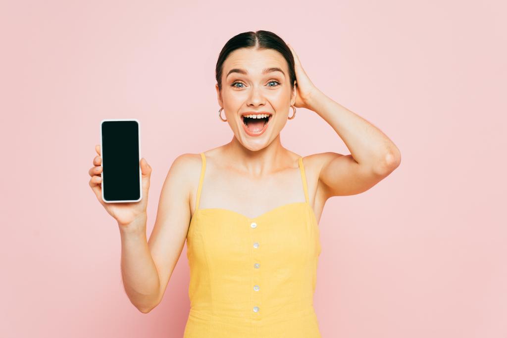 興奮したブルネットの女性はピンクに隔離された空白の画面でスマートフォンを保持 - 写真・画像