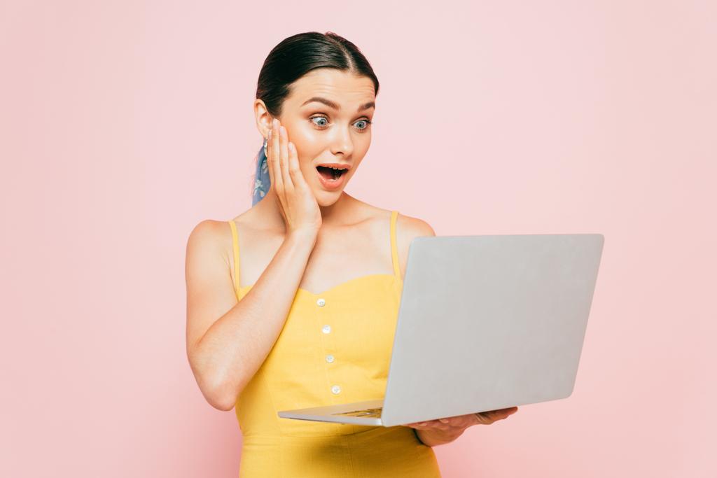shocked brunette young woman using laptop isolated on pink - Photo, Image