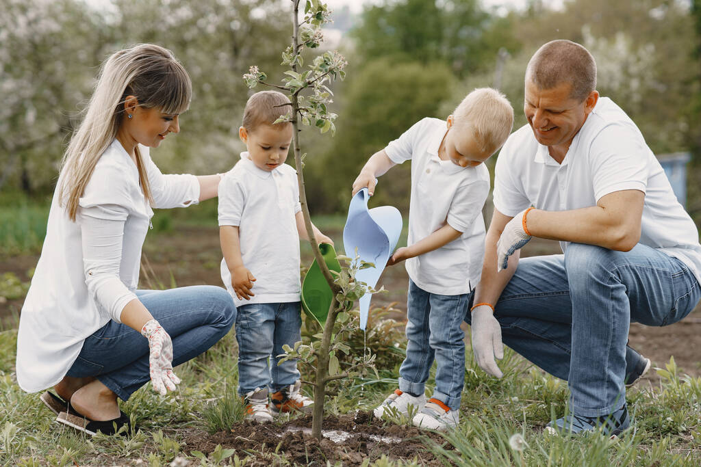 Familie mit kleinen Söhnen pflanzt einen Baum auf einem Hof - Foto, Bild