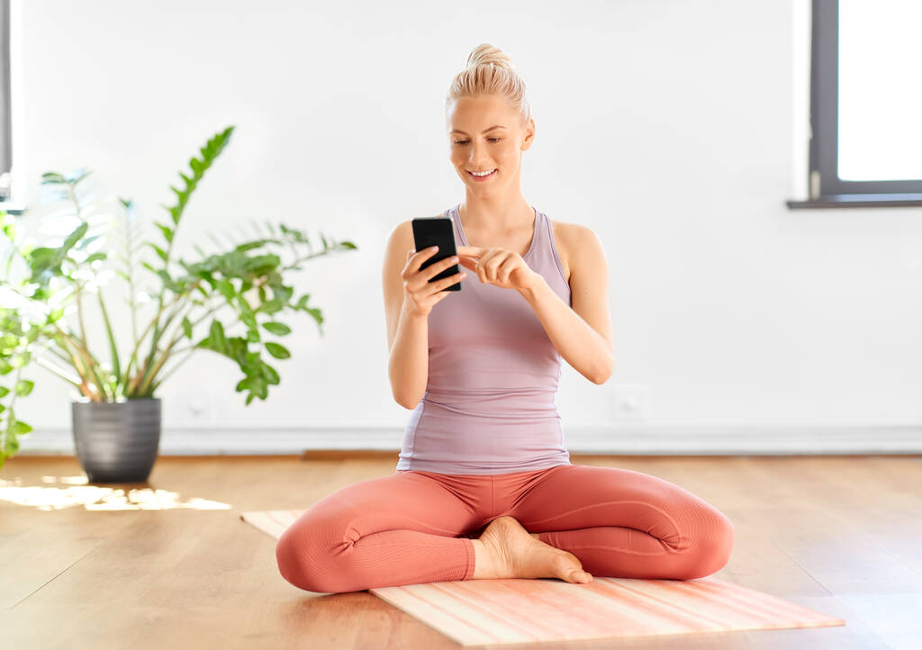 femme avec smartphone à la maison ou studio de yoga - Photo, image