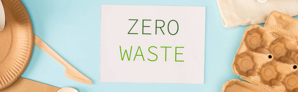 Panoramatická plodina karty s nulovým odpadem nápisy v blízkosti jednorázového stolního a lepenkového podnosu na modrém pozadí, koncept ekologie - Fotografie, Obrázek