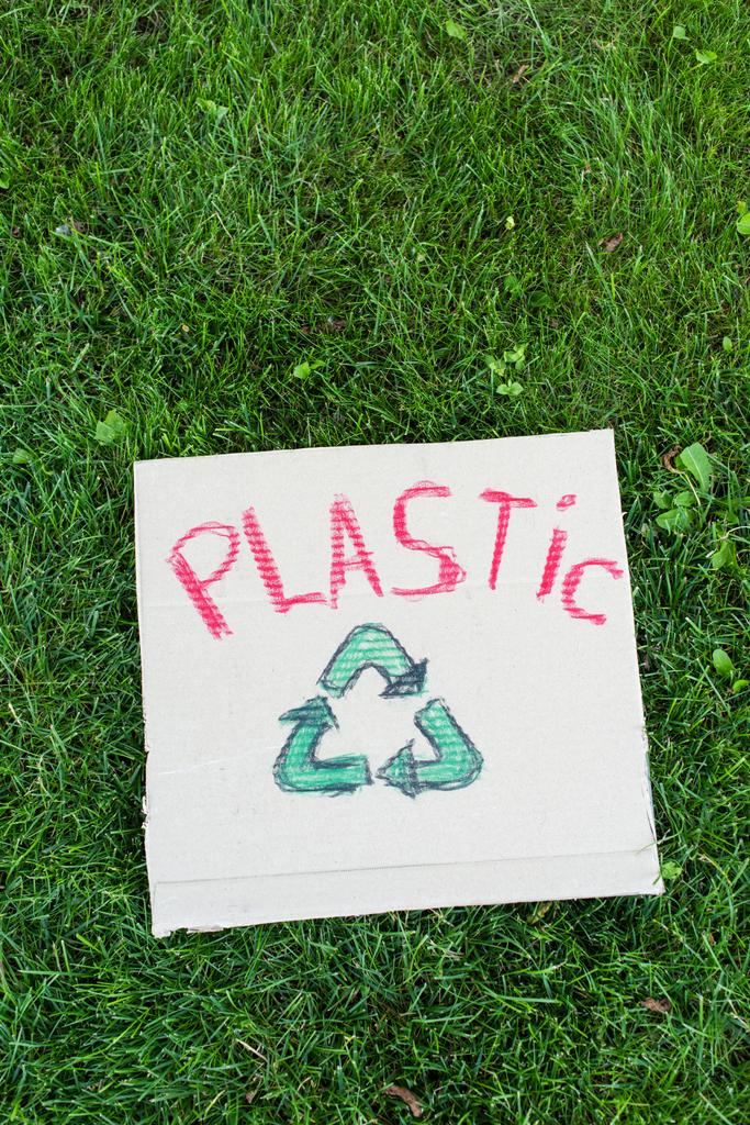 Vista superior de la pancarta con letras de plástico y el cartel de reciclaje en la hierba, concepto de ecología - Foto, imagen