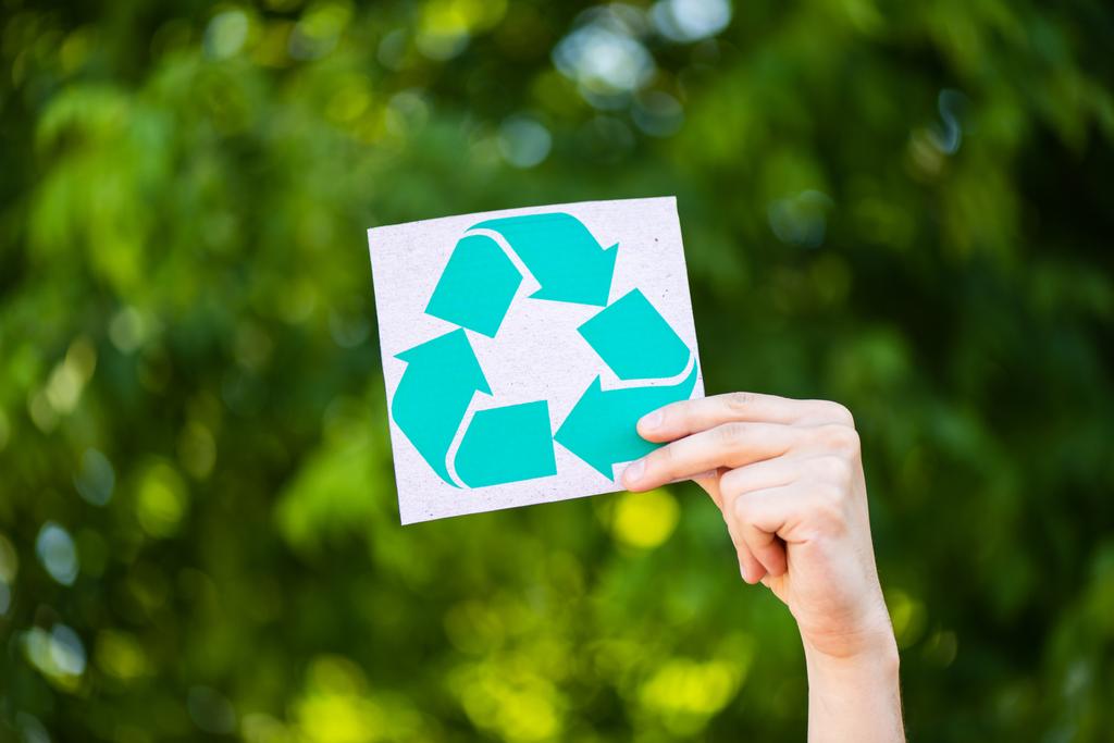 Vue recadrée de l'homme tenant la carte avec signe de recyclage à la main à l'extérieur, concept d'écologie - Photo, image