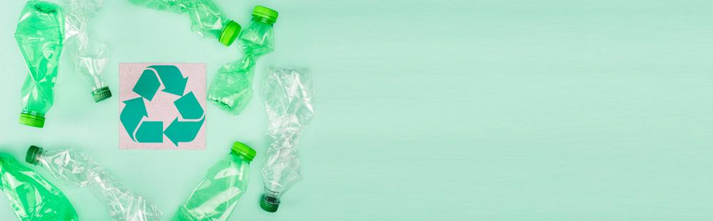 Panoraama käsite rypistynyt muovipulloja lähellä korttia kierrätys symboli vihreällä pohjalla, ekologia käsite - Valokuva, kuva