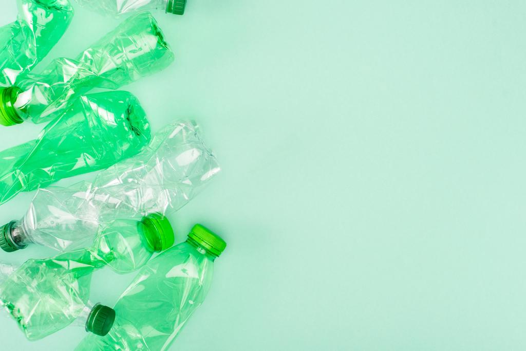 Vista superior de botellas de plástico arrugadas sobre fondo verde con espacio de copia, concepto de ecología - Foto, imagen