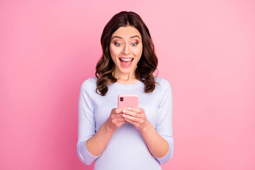 Fénykép a gyönyörű vonzó hölgy göndör frizura tartsa telefon kezét online szabadúszó munka karantén olvasás fizetés sms viselni alkalmi fehér pulóver elszigetelt pasztell rózsaszín háttér - Fotó, kép