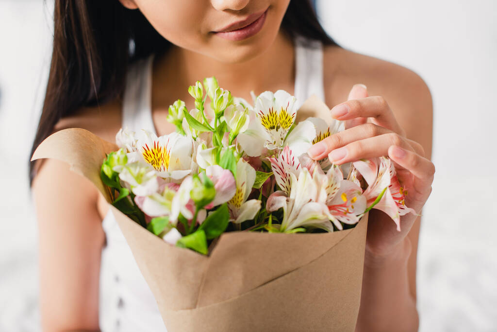 Vue recadrée de jeune femme touchant des fleurs en bouquet  - Photo, image