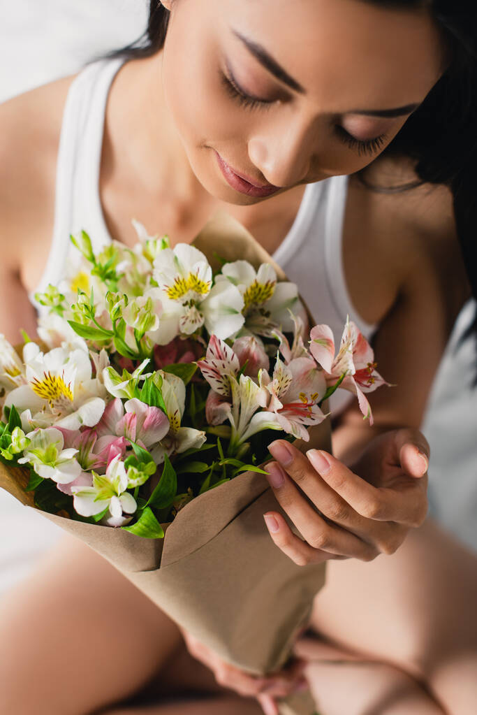 Vista ad alto angolo di donna asiatica in possesso di bouquet di alstroemeria a casa - Foto, immagini