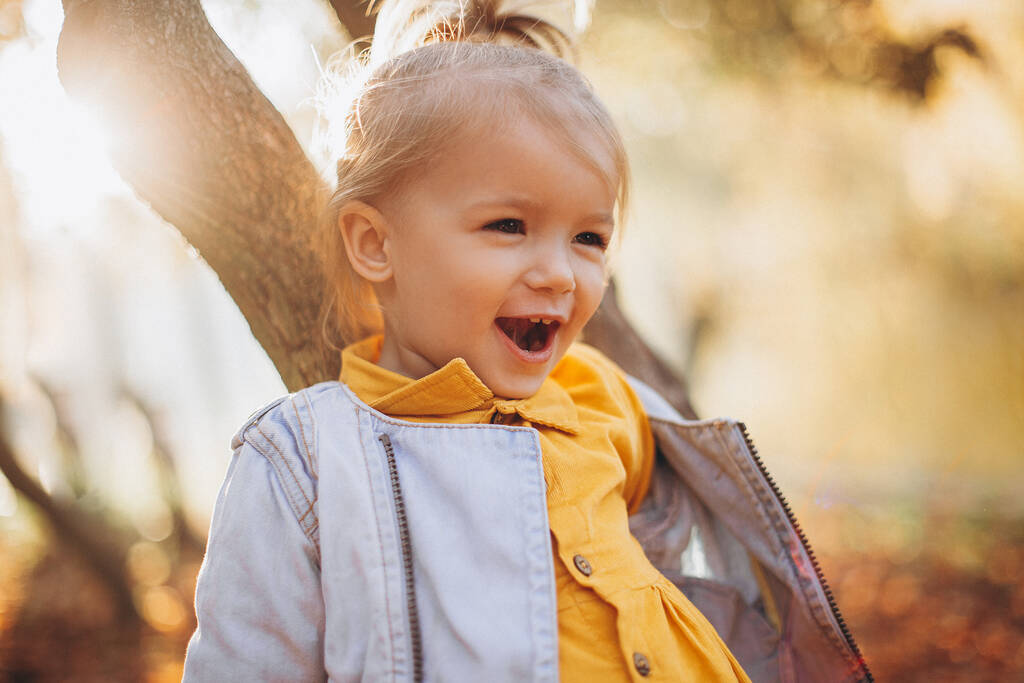 fröhliches Kind lacht und spielt mit Eltern im herbstlichen Stadtpark - Foto, Bild