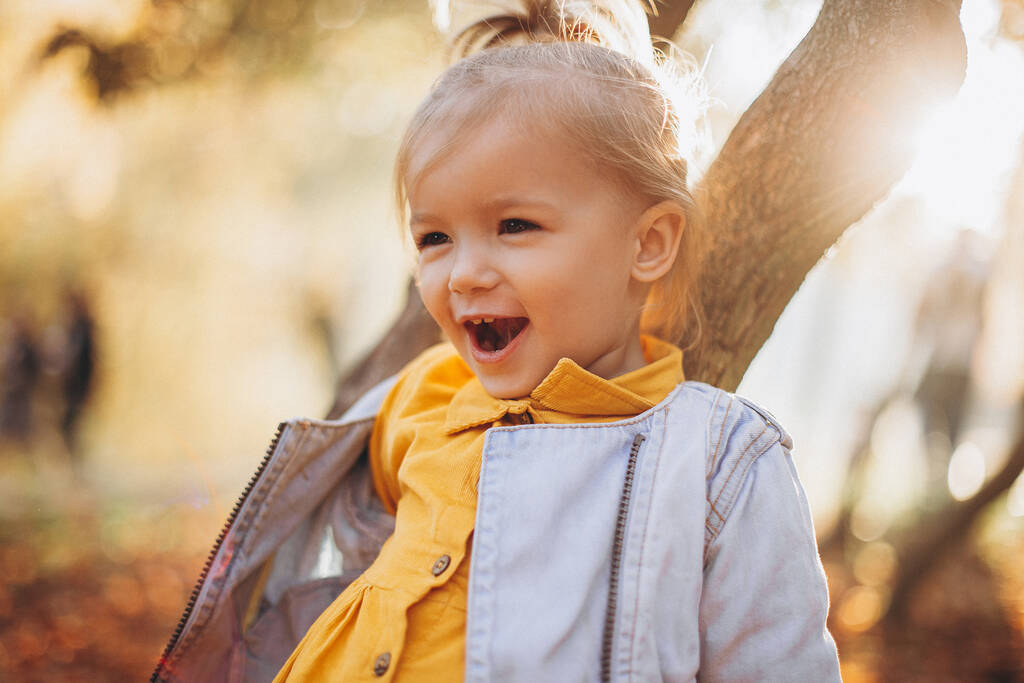 malá hezká dívka pózující na focení při procházce s rodiči v podzimním parku, nekonečně šťastné a radostné dítě, selektivní soustředění, efekt šumu - Fotografie, Obrázek