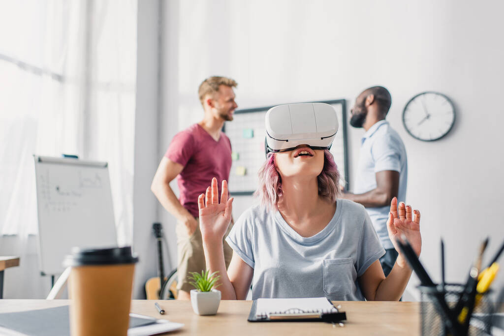 Selektiver Fokus der Geschäftsfrau mit vr-Headset, während multikulturelle Geschäftsleute im Büro reden  - Foto, Bild