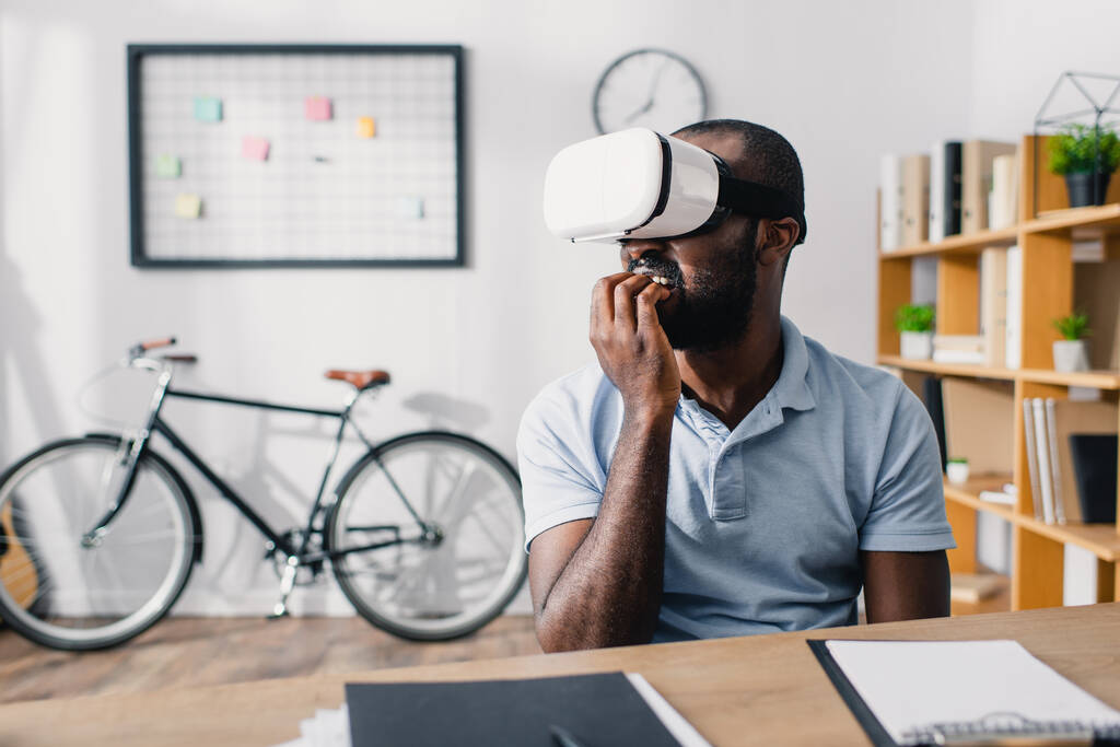 Selective focus of scared african american businessman using vr headset in office  - Photo, Image