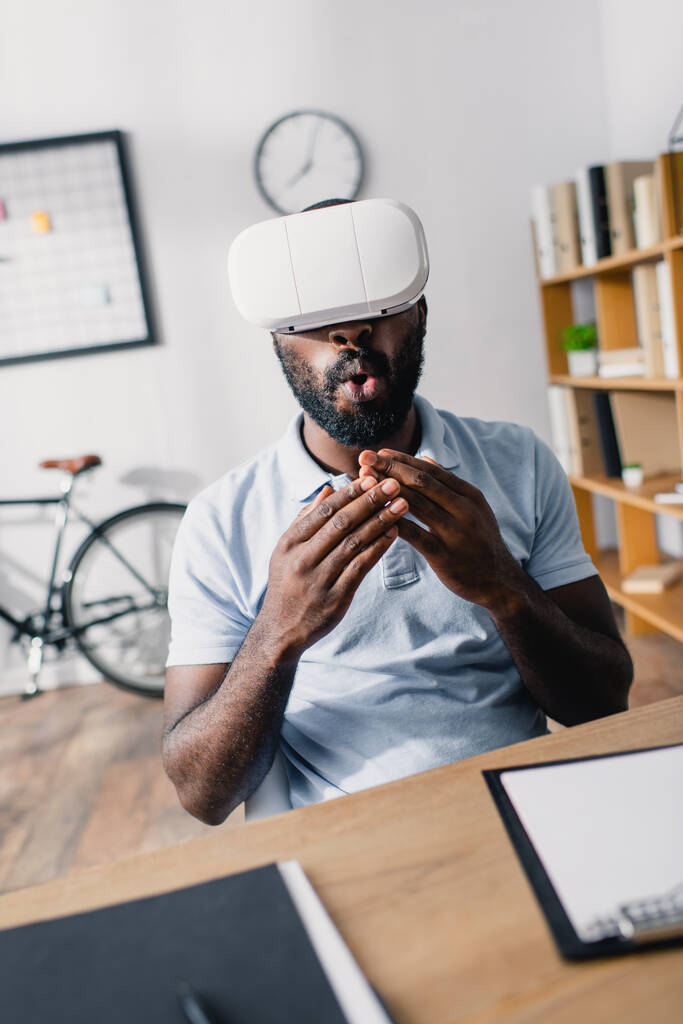 Focus selettivo di eccitato uomo d'affari afro-americano utilizzando cuffie realtà virtuale in ufficio  - Foto, immagini