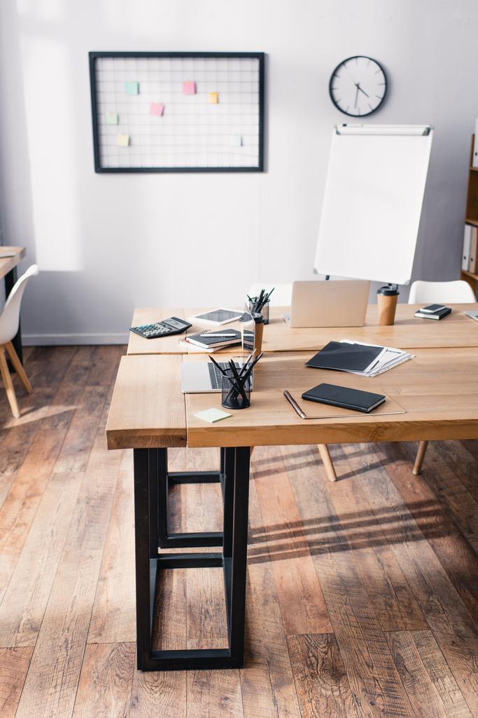 Канцелярские принадлежности, цифровые приборы и кофе на деревянных столах в офисе  - Фото, изображение