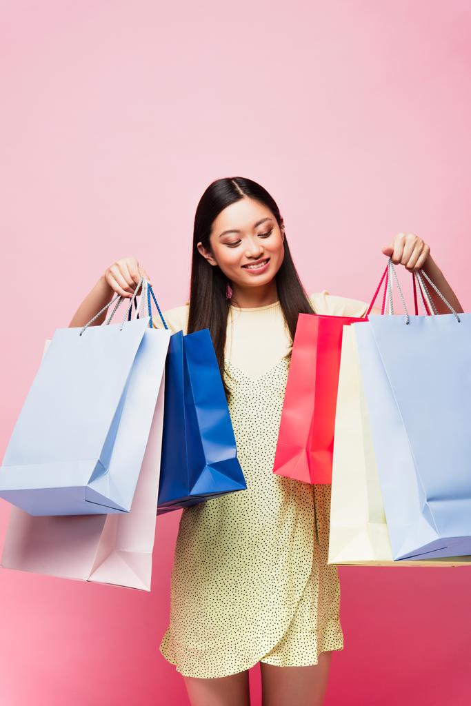 allegro asiatico ragazza guardando shopping borse su rosa  - Foto, immagini