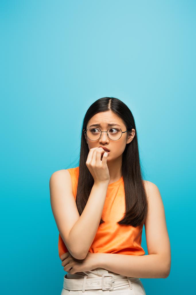 giovane e preoccupato asiatico donna toccare bocca su blu  - Foto, immagini
