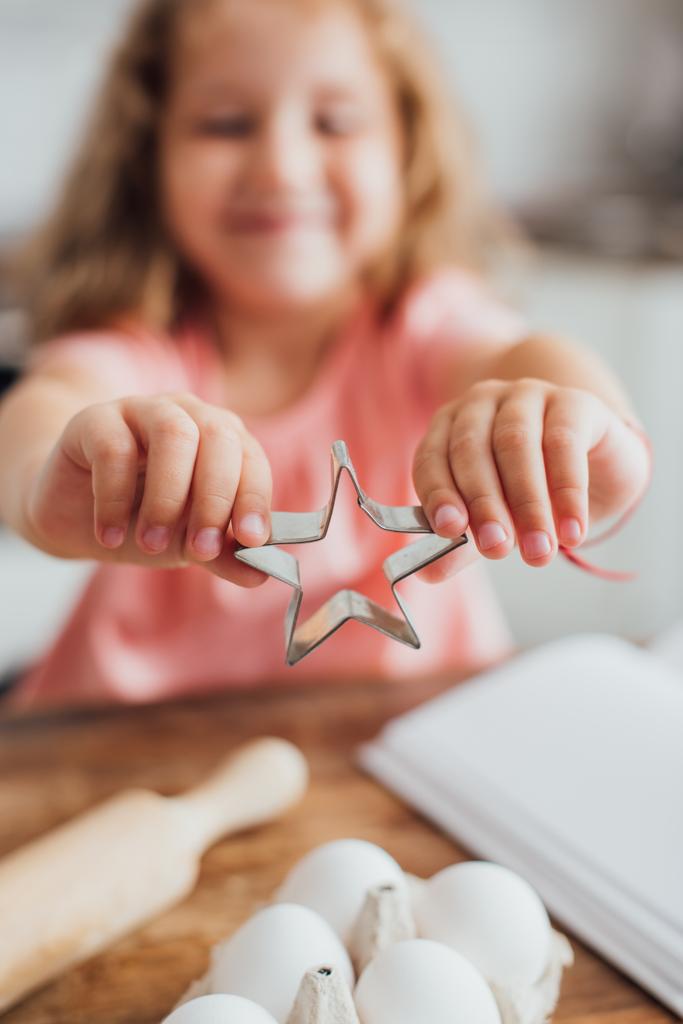 selective focus of kid showing star-shaped cookie cutter near chicken eggs - Photo, Image