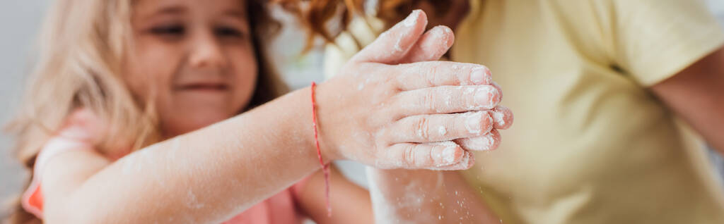 partial view of a daughter with hands in flour near mother, selective focus, horizontal image - Photo, Image
