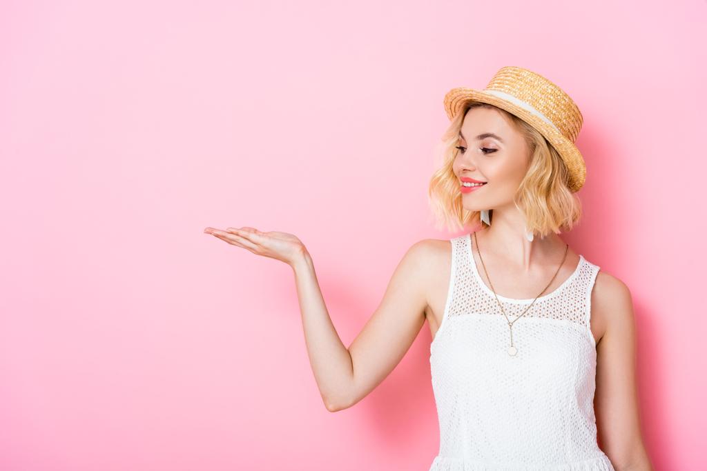young woman in straw hat and dress pointing with hand on pink  - Photo, Image