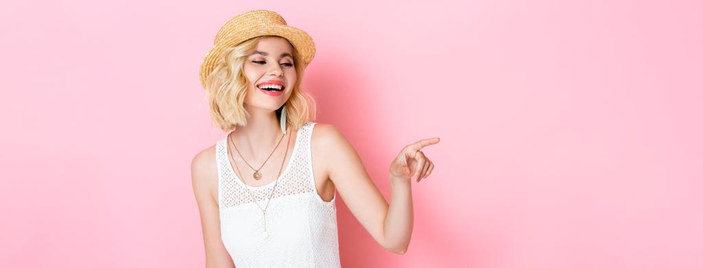 horizontal image of woman in straw hat laughing and pointing with finger on pink  - Photo, Image