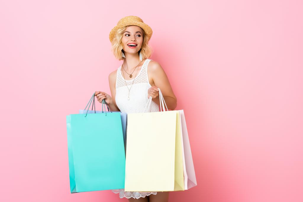excited woman in straw hat and white dress holding shopping bags on pink  - Photo, Image