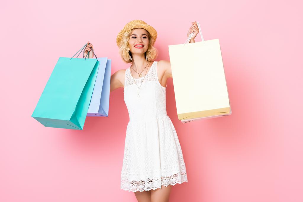 藁帽子の若い女性とピンクのショッピングバッグを持っているドレス  - 写真・画像